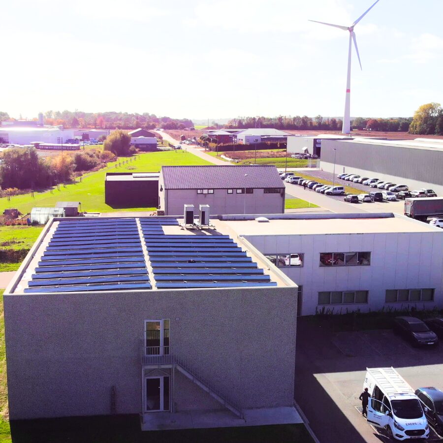Hauptsitz und Produktion von Micromega Dynamics in Belgien, mit Solarmodulen und einer Windenergieanlage im Hintergrund